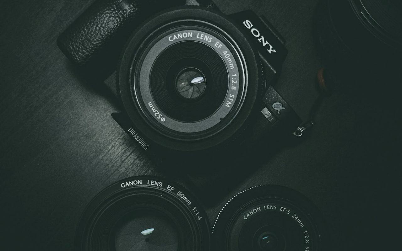 A professional DSLR camera and lenses on a dark surface